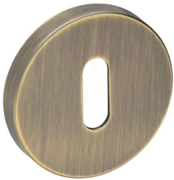 Okrągła, mosiężna osłona zamka z wąskim otworem w kształcie prostokąta.