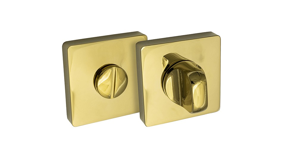 Złote, kwadratowe elementy mechanizmu zamka, jeden z pokrętłem, drugi z wcięciem.