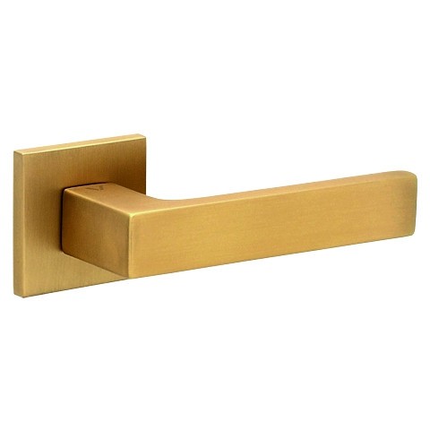 Złoty uchwyt drzwiowy o prostokątnym kształcie, zamocowany na kwadratowej podstawie.