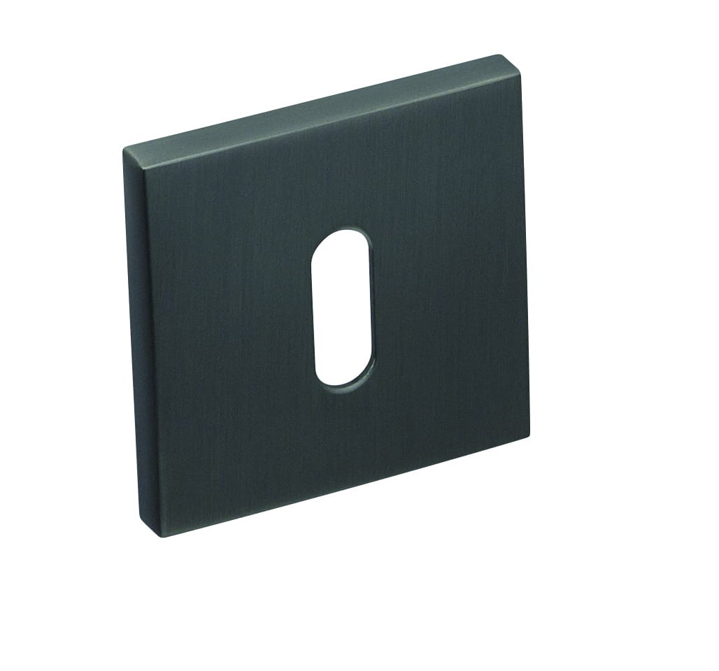 Kwadratowa, ciemna osłona z otworem, przeznaczona do montażu na ścianie lub włącznika.