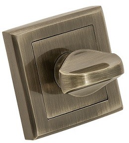 Metalowy włącznik światła w odcieniach brązu, z okrągłym pokrętłem na kwadratowej podstawie.