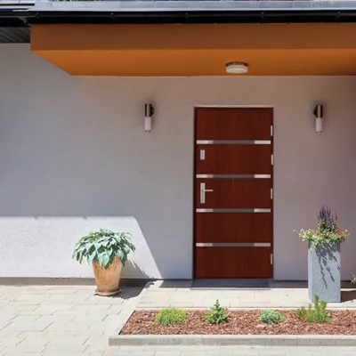 Eleganckie wejście z drewnianymi drzwiami, roślinami w donicach i nowoczesnym oświetleniem.