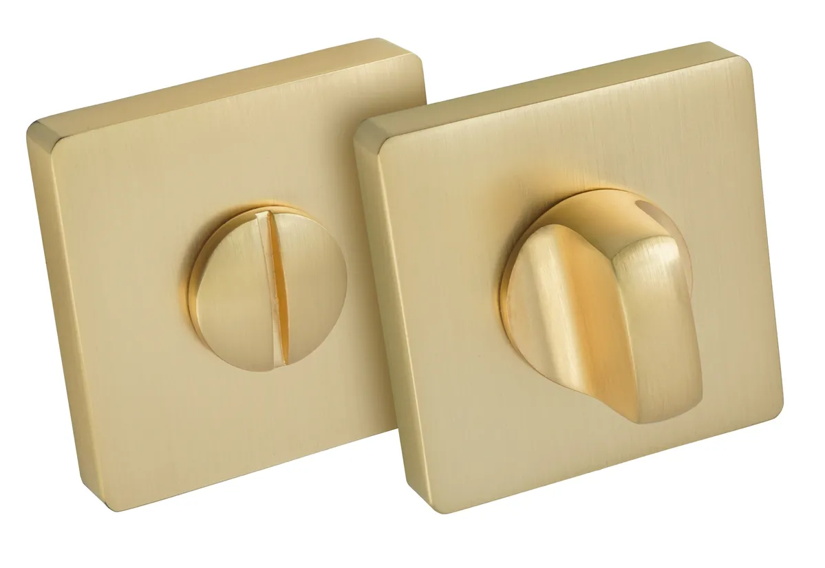 Złote, kwadratowe pokrętła do drzwi, jedno z otworem na klucz, drugie z wypukłym uchwytem.