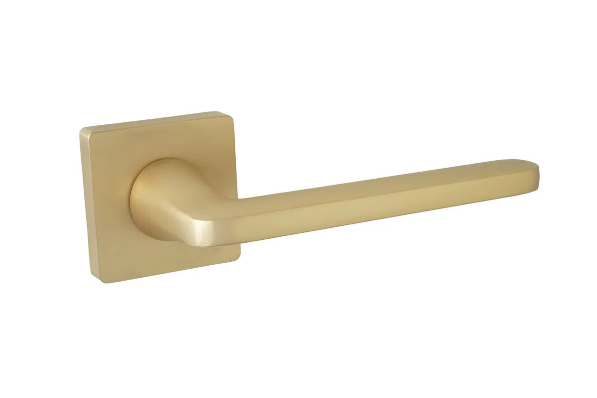 Złota klamka drzwiowa o prostym, nowoczesnym kształcie i kwadratowej podstawie.