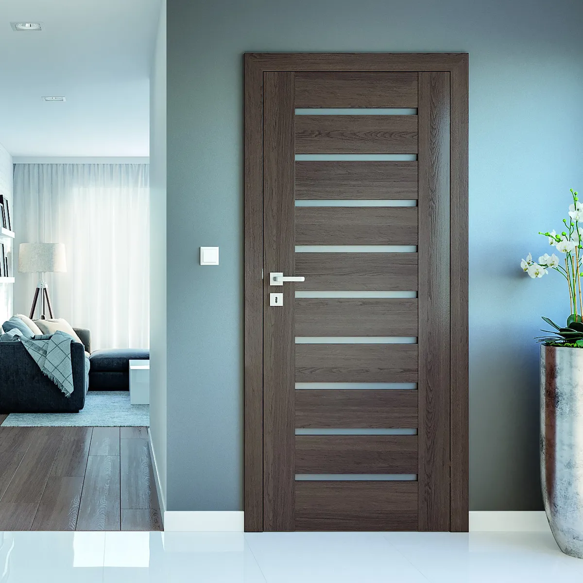 Nowoczesne drzwi w odcieniu drewna, prowadzące do jasnego pomieszczenia z kanapą i lampą. Obok kwiaty w doniczce.