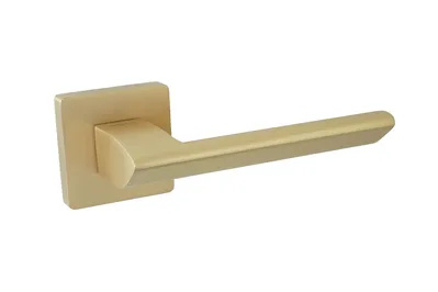 Złota klamka drzwiowa o nowoczesnym, prostym designie na kwadratowej podstawie.